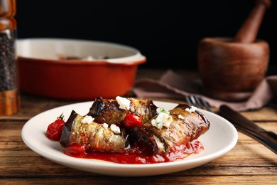 Photo of Tasty eggplant rolls served on wooden table, closeup
