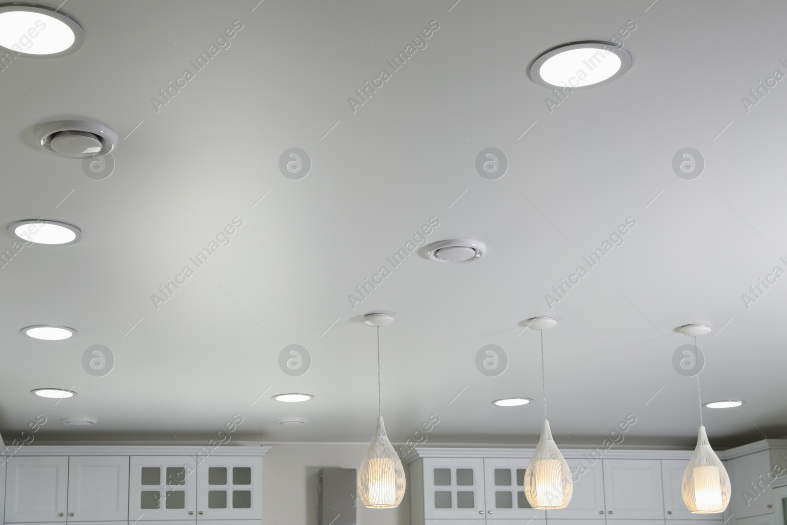 Photo of Modern pendant lamps on white ceiling indoors