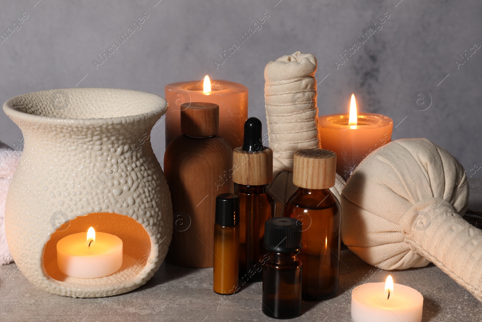 Photo of Aromatherapy. Scented candles and spa products on gray textured table, closeup