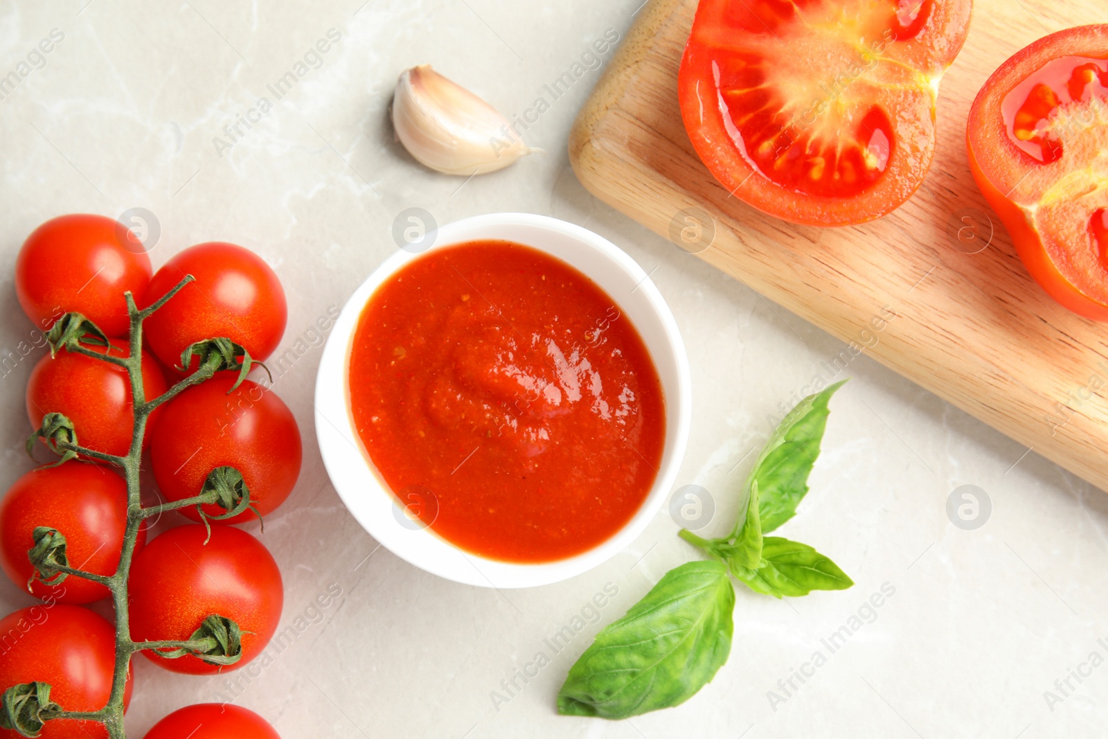 Photo of Flat lay composition with bowl of sauce and tomatoes on light table