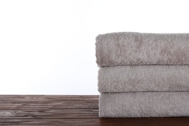 Photo of Fresh towels on wooden table against white background. Space for text