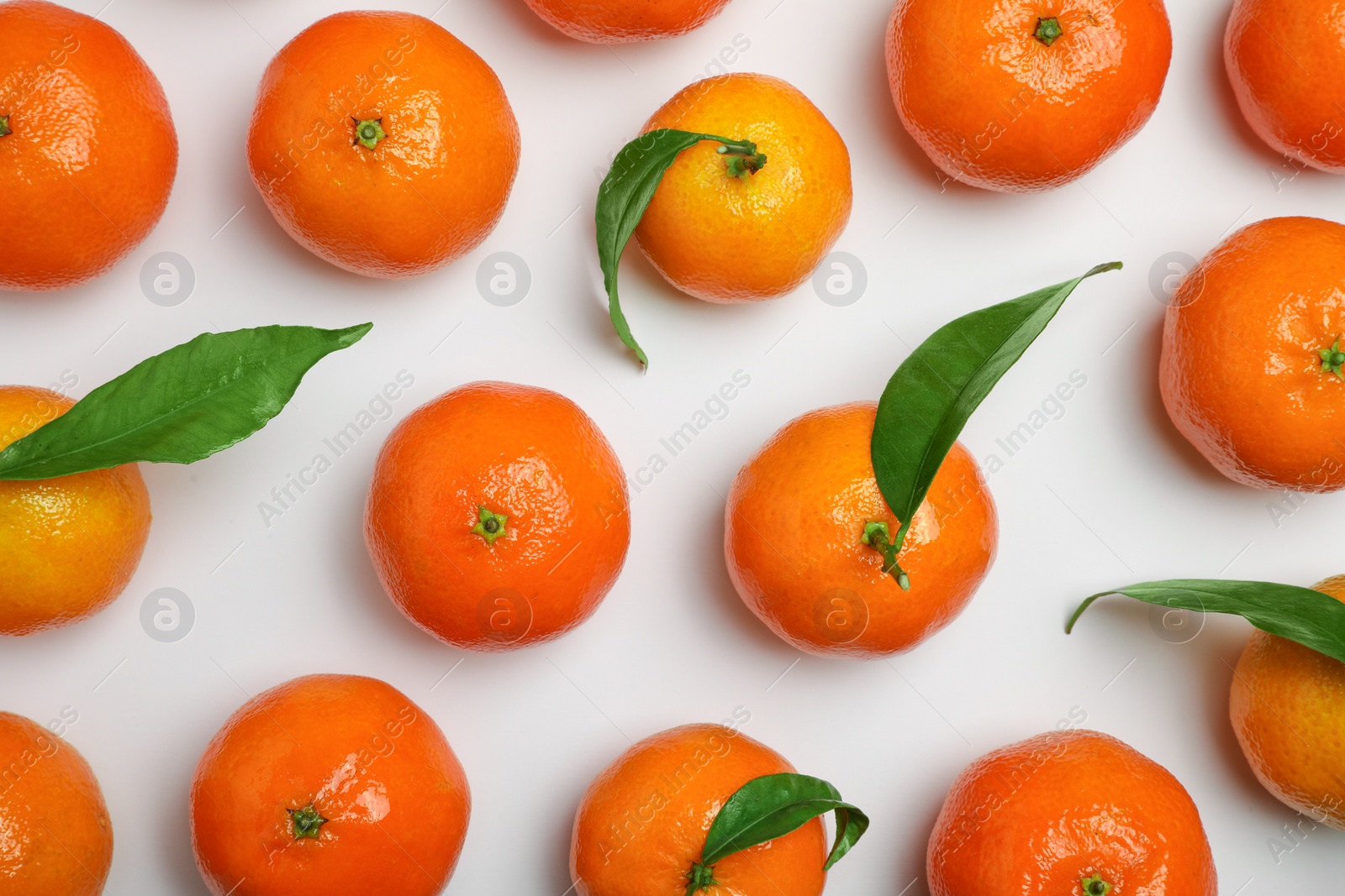 Photo of Delicious tangerines and green leaves on white background, flat lay