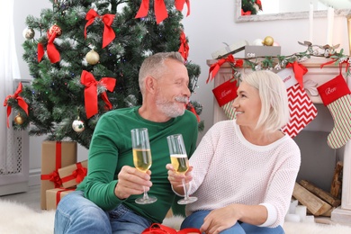 Photo of Mature couple with glasses of champagne at home. Christmas celebration