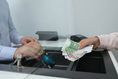 Photo of Woman putting money on card in bank, closeup. Currency exchange