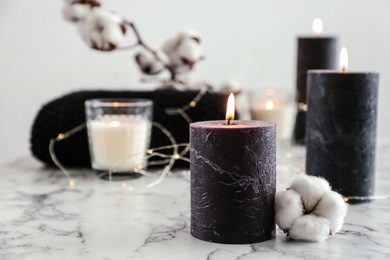 Burning candles and cotton flower with fairy lights on marble table