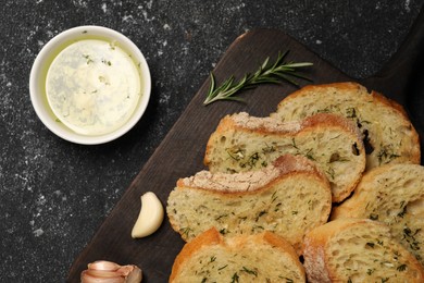 Photo of Tasty baguette with garlic served on grey textured table, flat lay