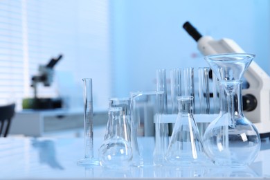 Photo of Laboratory analysis. Different glassware and microscope on white table indoors, space for text