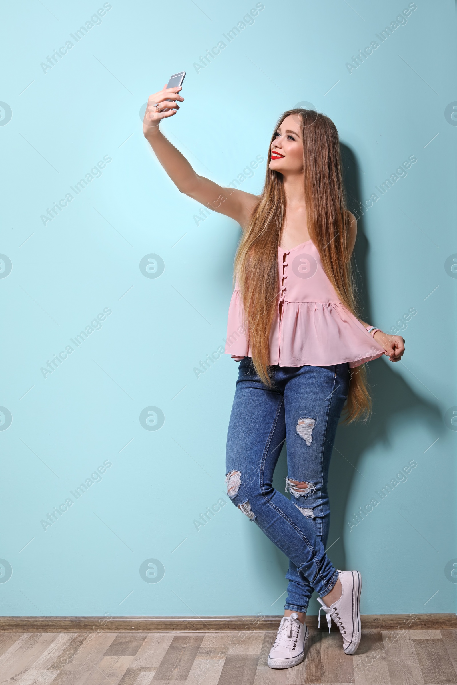 Photo of Attractive young woman taking selfie near color wall