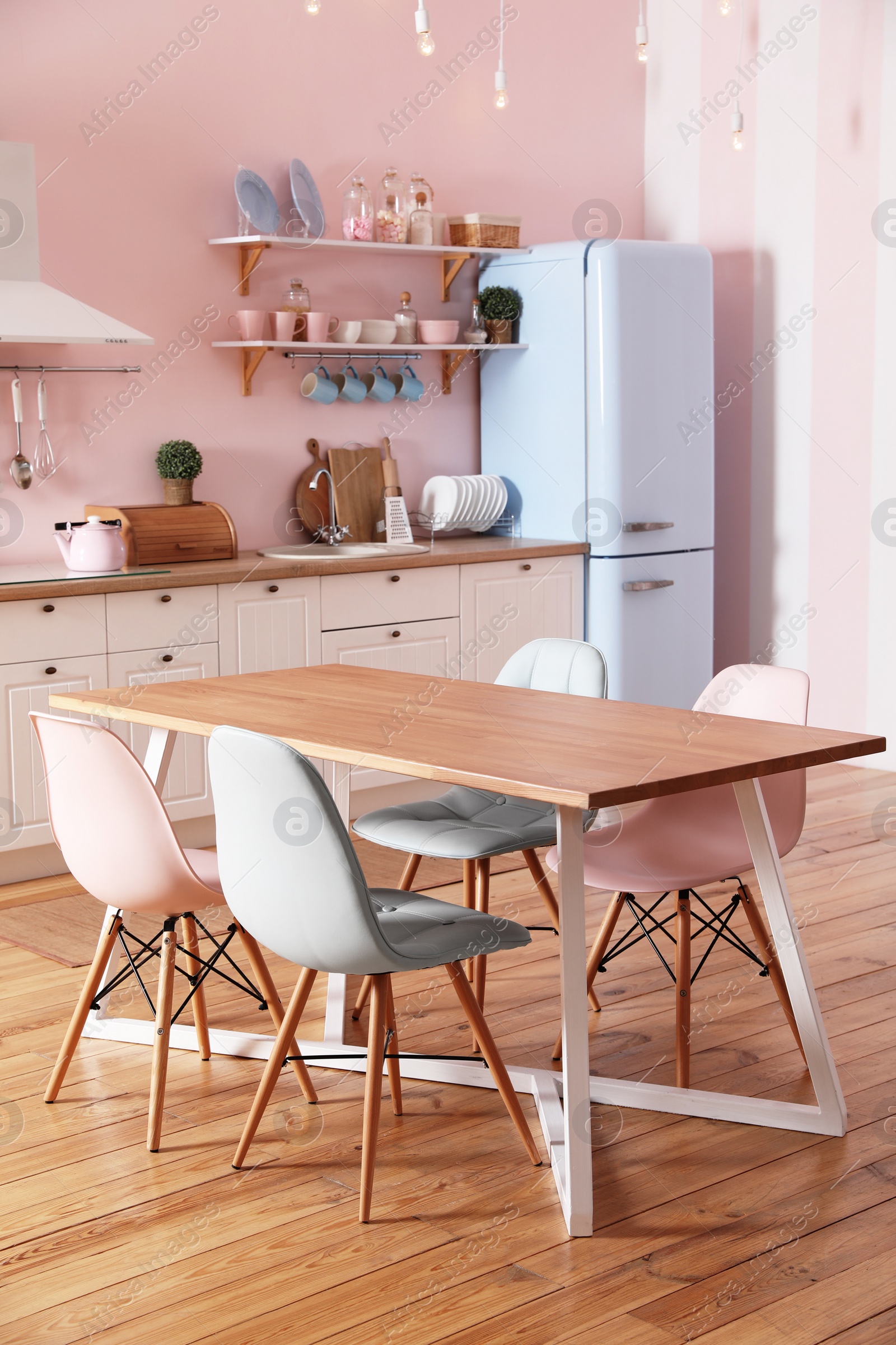 Photo of Stylish pink kitchen interior with dining table and chairs