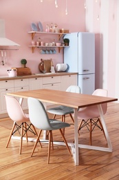 Stylish pink kitchen interior with dining table and chairs