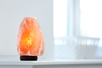 Himalayan salt lamp on table indoors. Space for text