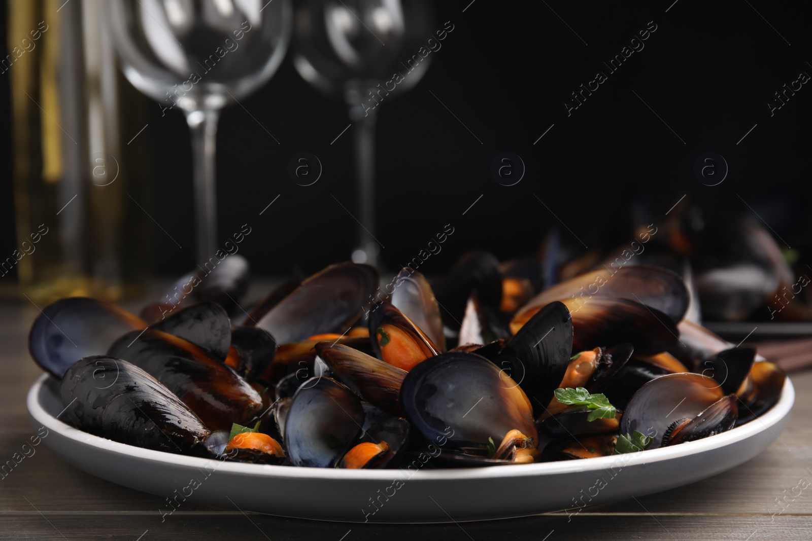 Photo of Plate of cooked mussels with parsley on table, closeup