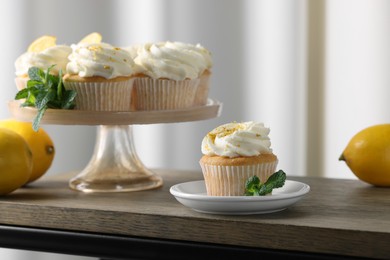 Delicious lemon cupcakes with white cream, mint and lemons on wooden table