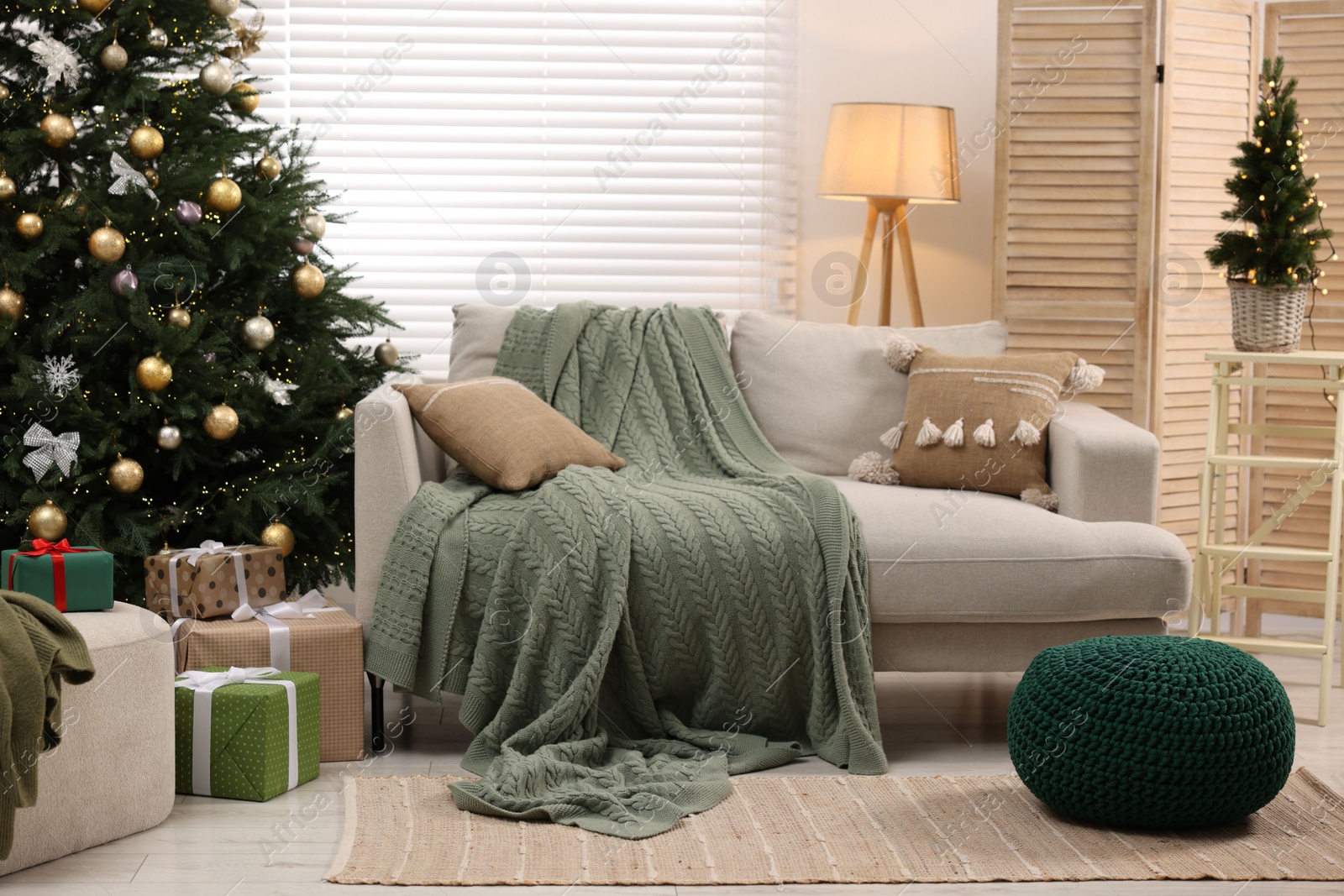 Photo of Sofa near Christmas tree in room. Festive interior design