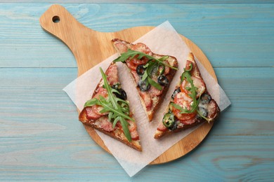 Tasty pizza toasts on light blue wooden table, top view