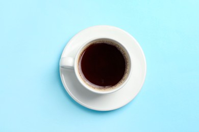 Cup of aromatic coffee on light blue background, top view