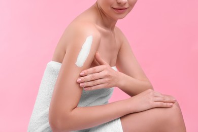 Photo of Woman with smear of body cream on her shoulder against pink background, closeup