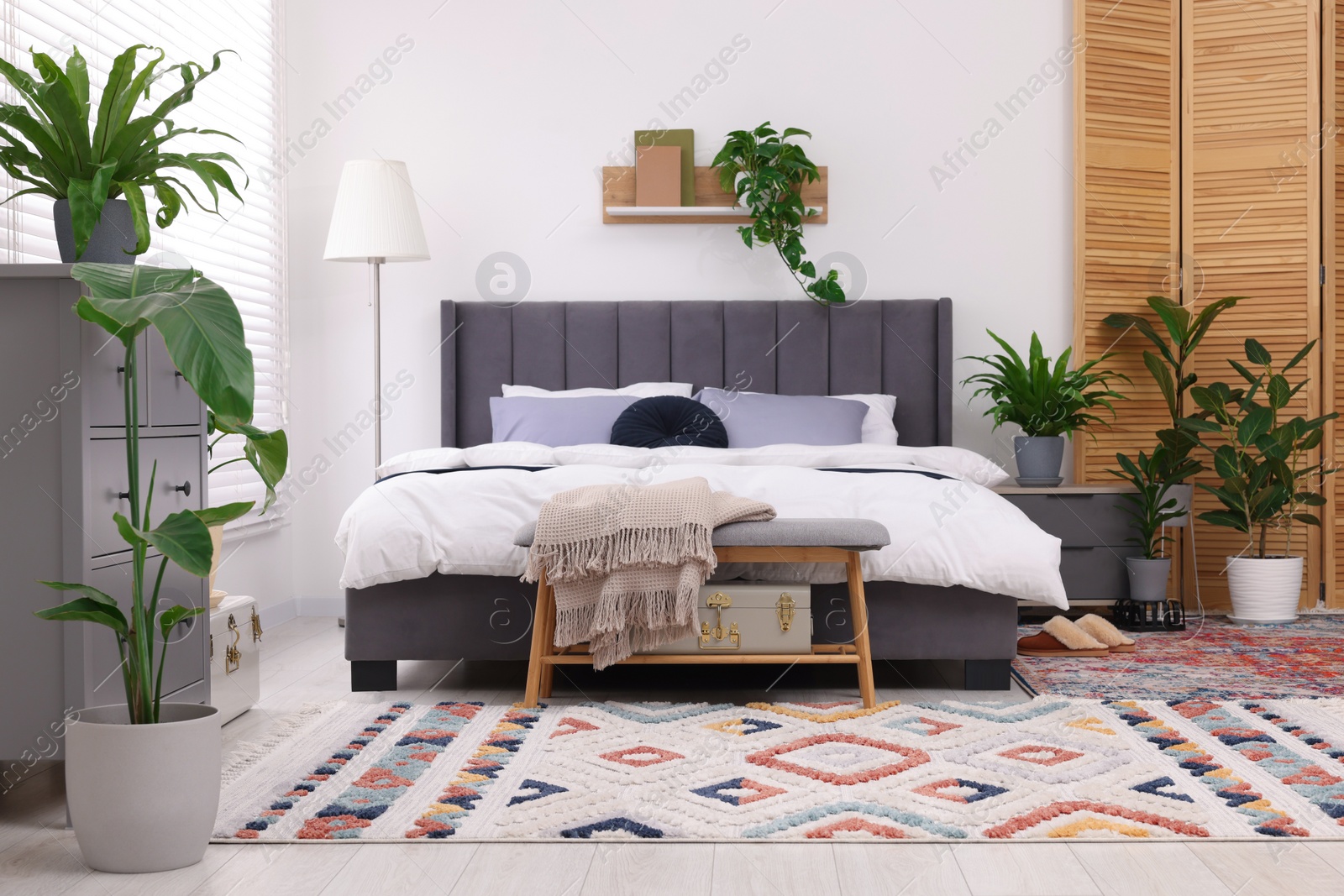 Photo of Stylish bedroom with double bed and beautiful green houseplants. Modern interior