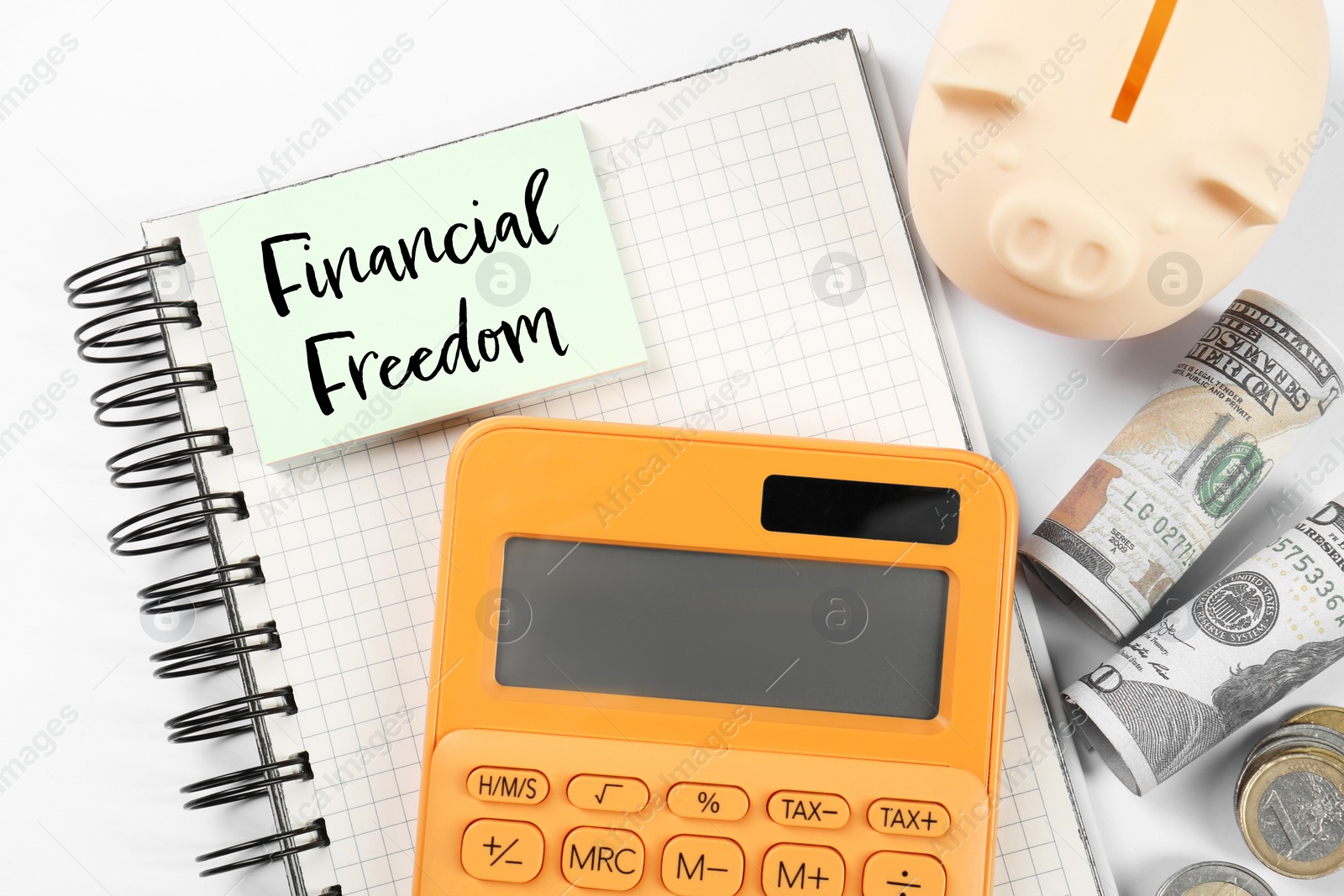 Image of Notebook with words Financial Freedom, piggy bank, dollars and calculator on white table, flat lay