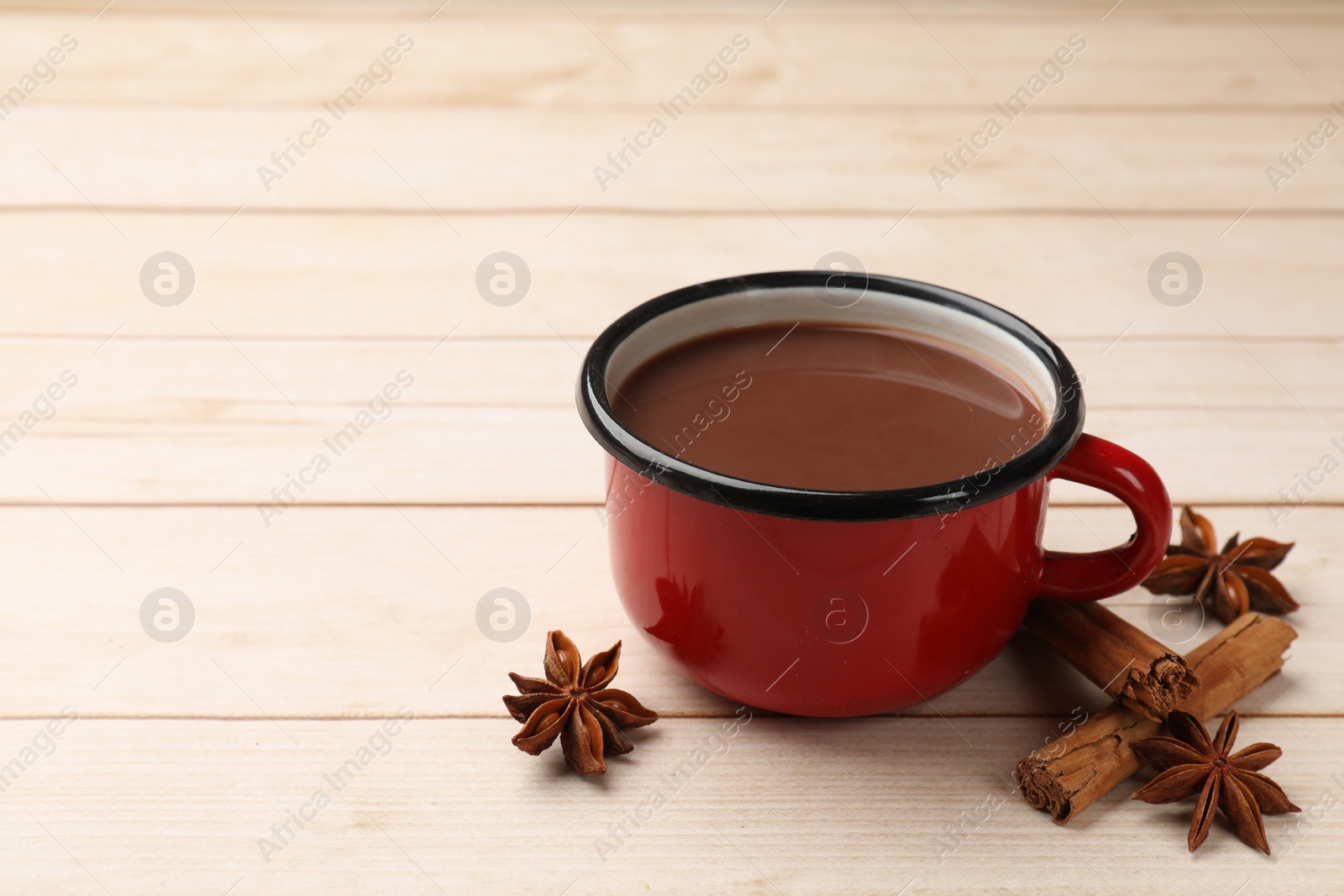 Photo of Tasty hot chocolate and spices on light wooden table, closeup. Space for text