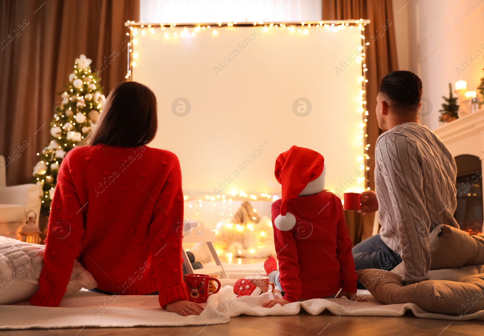 Photo of Family watching movie using video projector at home. Cozy Christmas atmosphere