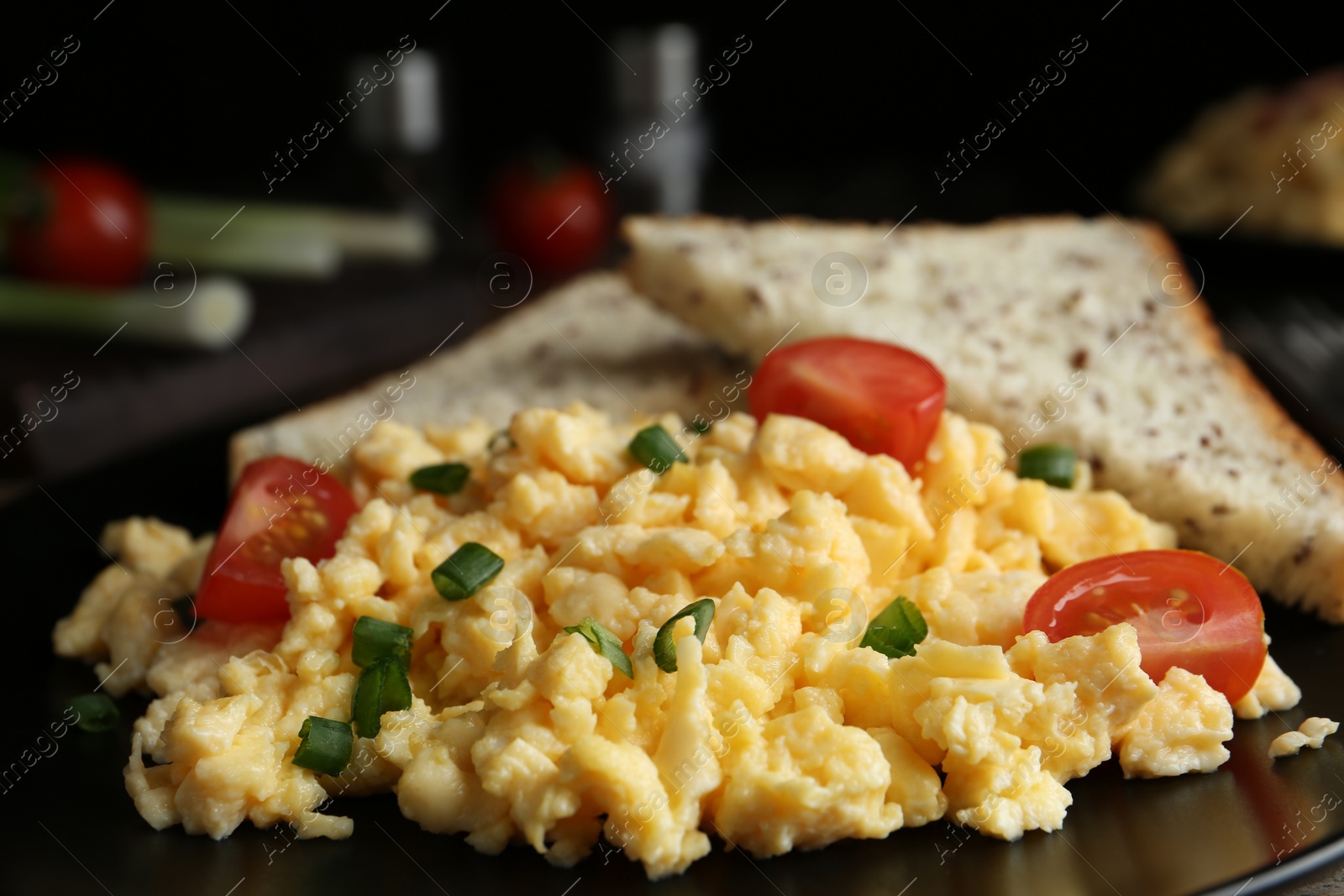 Photo of Tasty scrambled eggs with cherry tomato and bread on plate, closeup