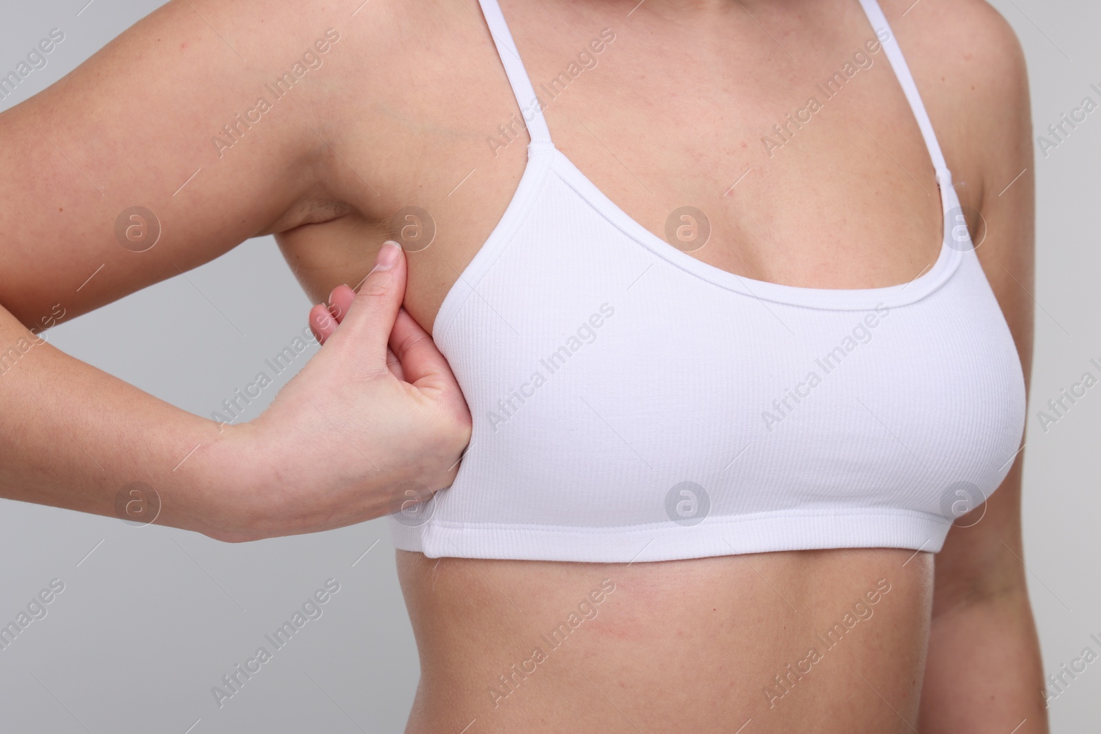 Photo of Mammology. Woman doing breast self-examination on light grey background, closeup