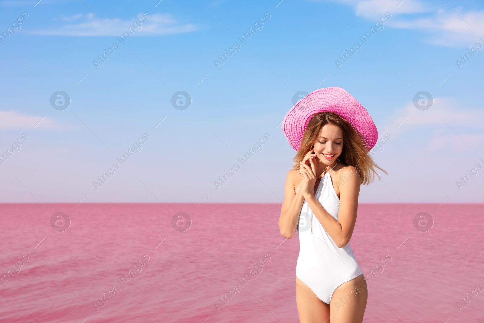 Photo of Beautiful woman in swimsuit posing near pink lake on sunny day