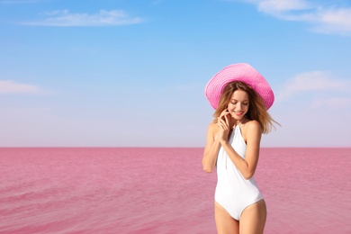 Photo of Beautiful woman in swimsuit posing near pink lake on sunny day