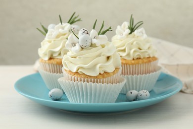 Photo of Tasty Easter cupcakes with vanilla cream on light wooden table, closeup