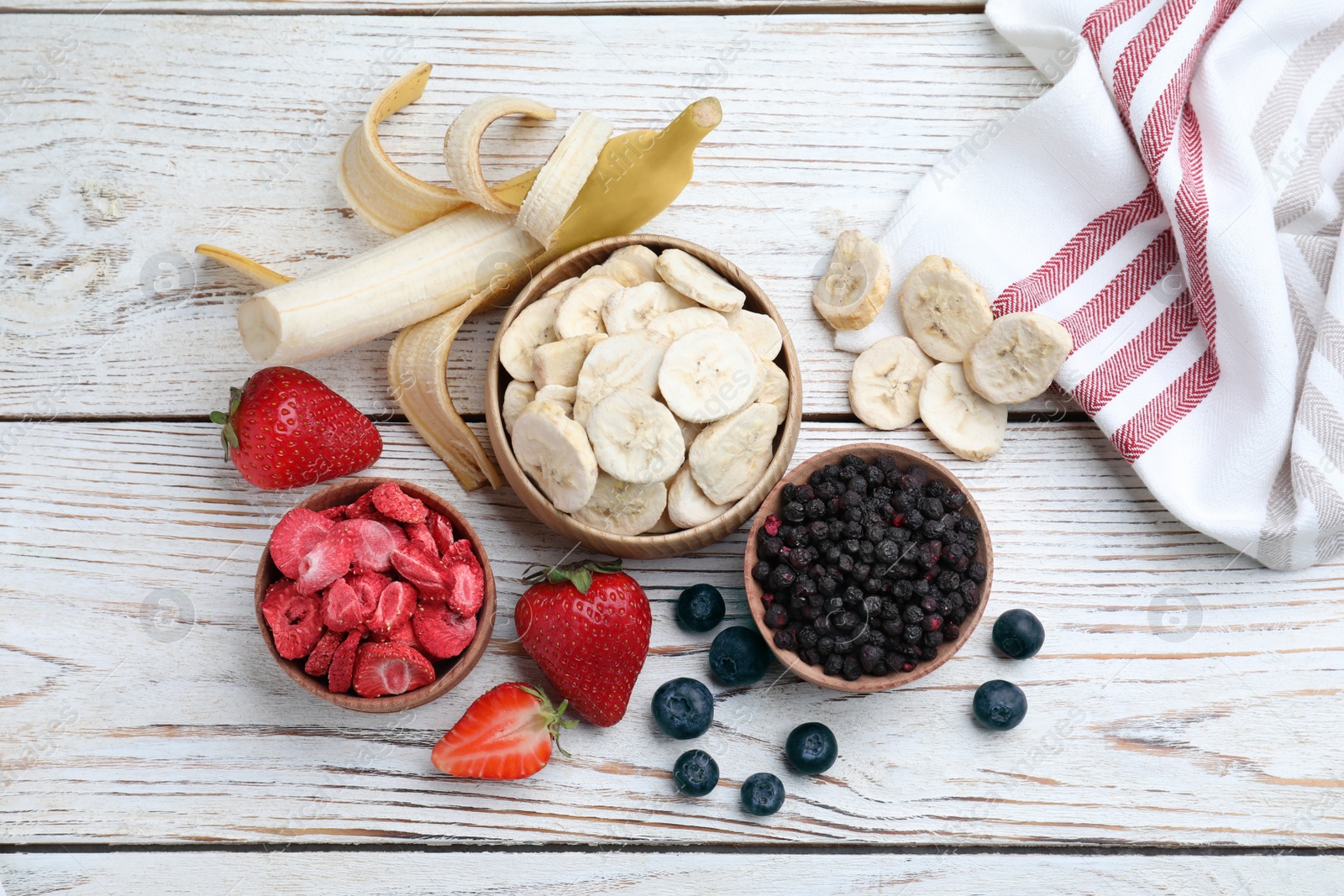 Photo of Different freeze dried and fresh fruits on white wooden table, flat lay