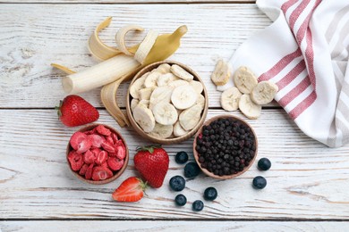 Photo of Different freeze dried and fresh fruits on white wooden table, flat lay