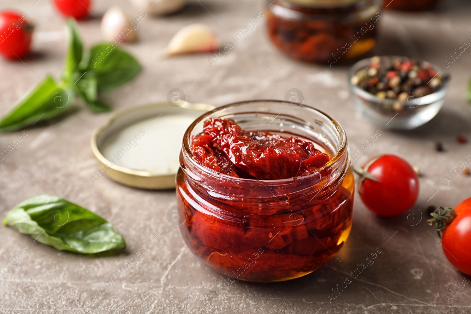 Photo of Dried tomatoes in glass jar on table. Healthy snack