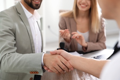 Photo of Business partners shaking hands at table after meeting in office, closeup