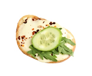 Slice of bread with spread, cucumber and arugula on white background, top view