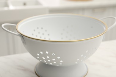 One clean colander on white table, closeup