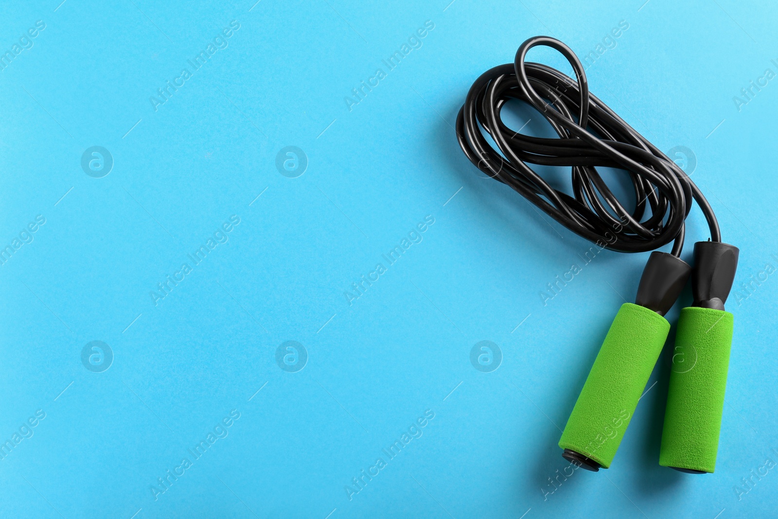 Photo of Skipping rope on light blue background, top view. Space for text