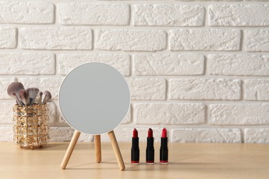 Mirror and makeup products on wooden dressing table in room. Space for text