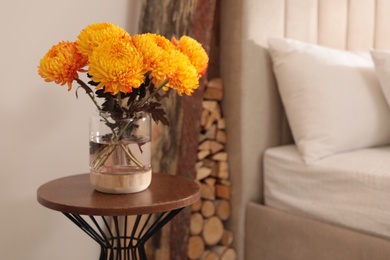 Photo of Beautiful autumn flowers on table in cozy bedroom interior. Space for text