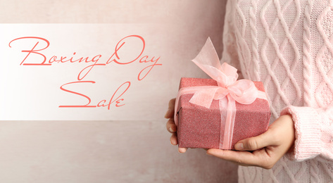 Boxing day sale. Woman with gift on light background, banner design