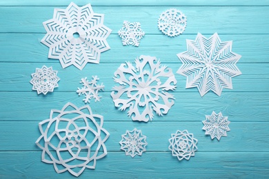 Photo of Flat lay composition with paper snowflakes on blue wooden background. Winter season
