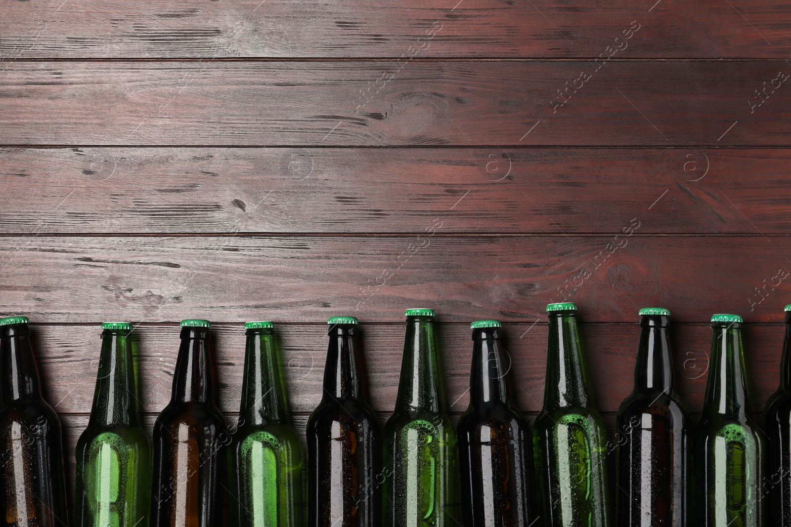 Photo of Glass bottles of beer on wooden background, flat lay. Space for text