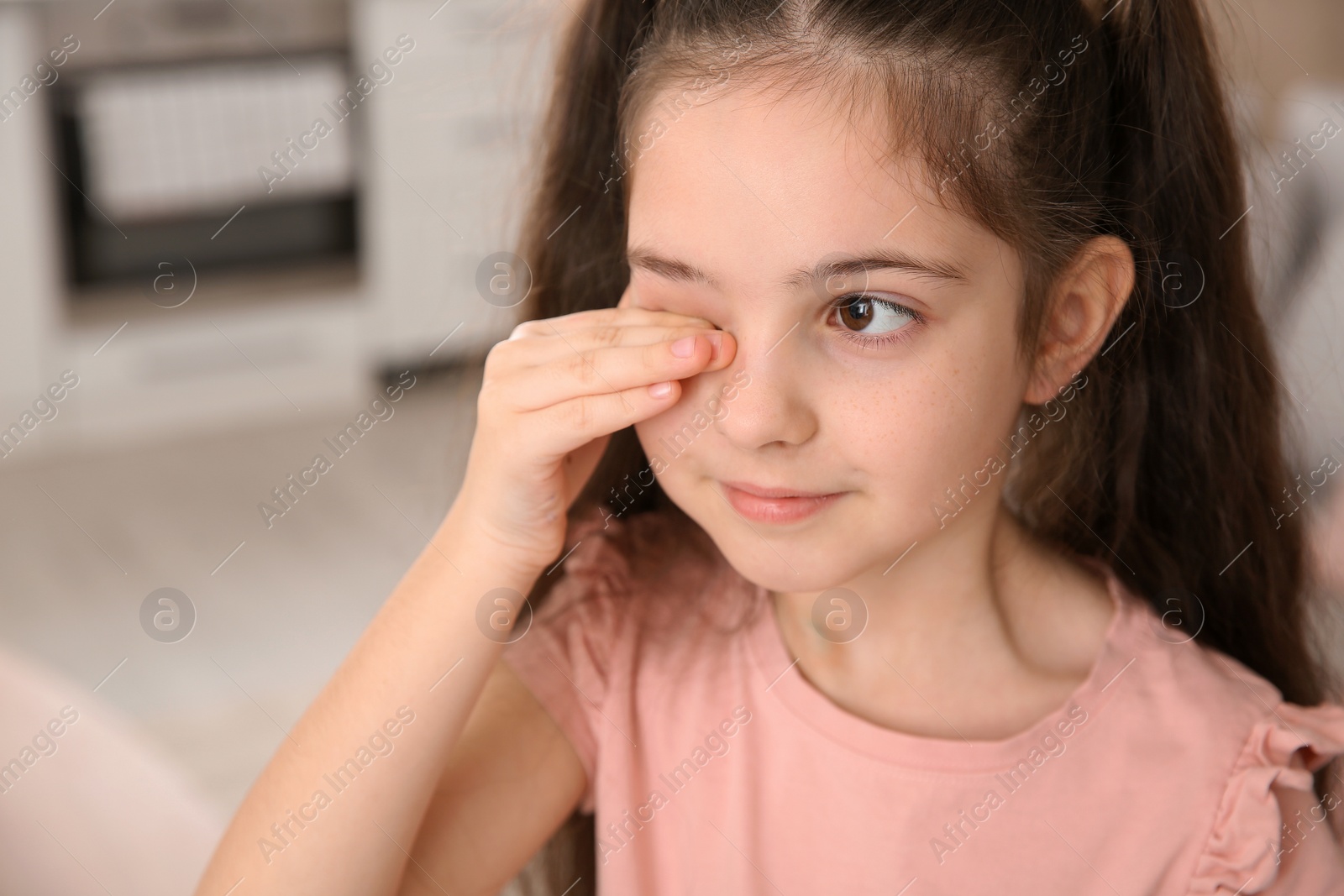 Photo of Little girl rubbing eye at home. Annoying itch