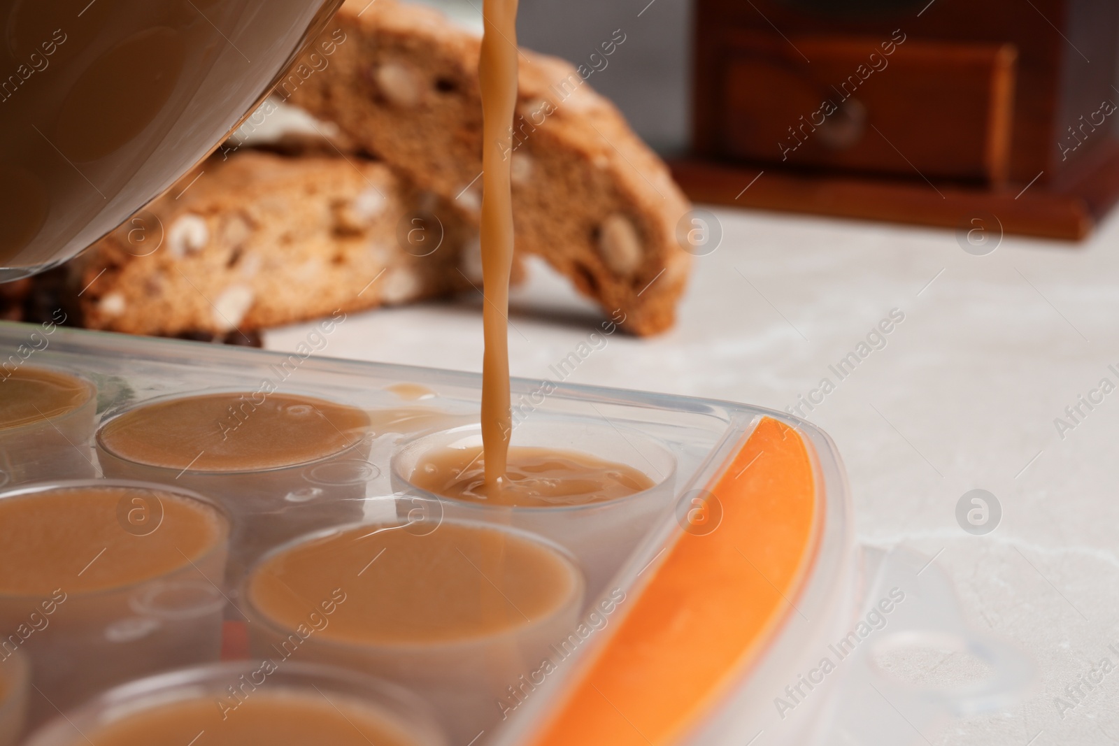 Photo of Pouring coffee drink into ice cube tray on table, closeup