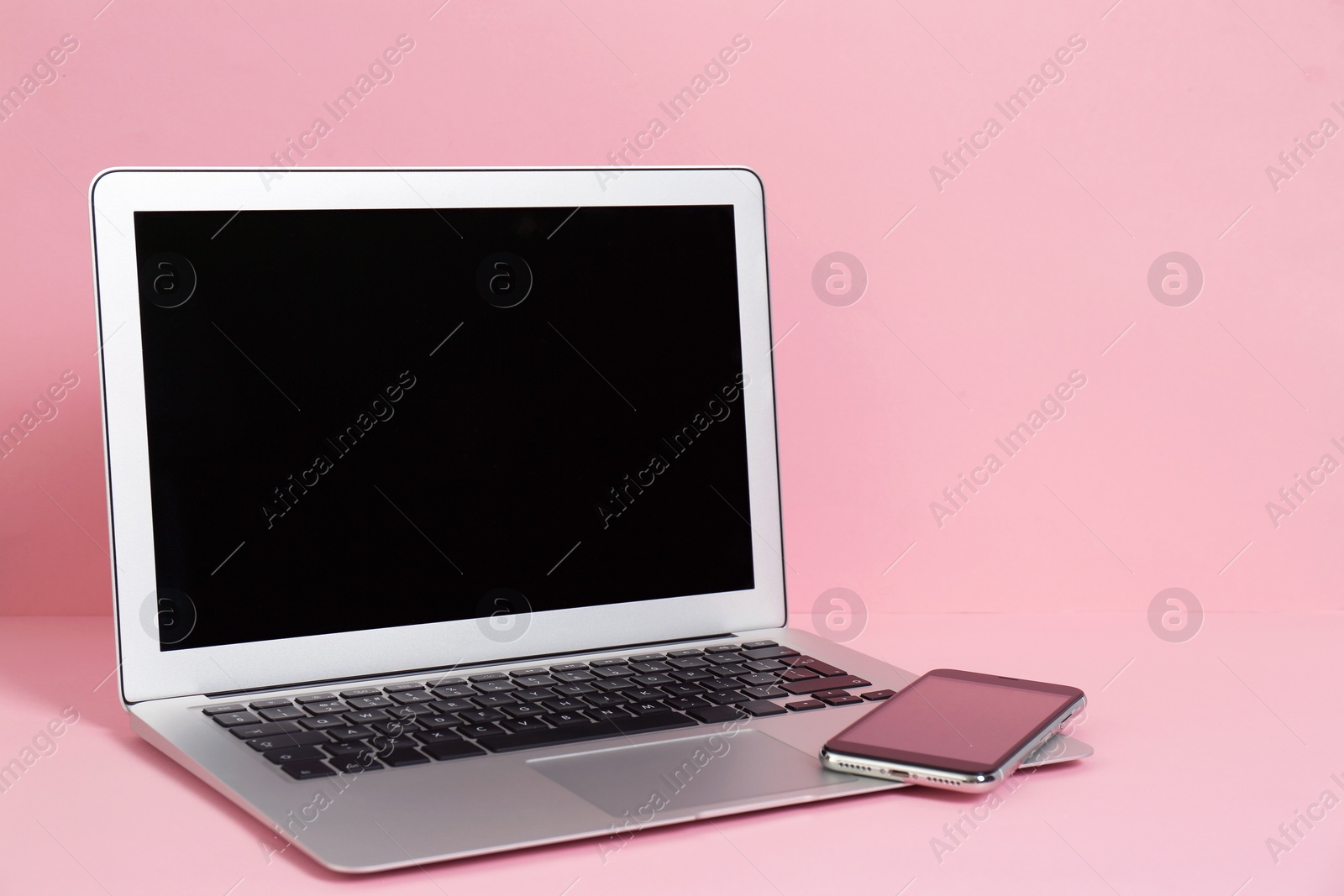 Photo of Modern laptop and mobile phone on color background