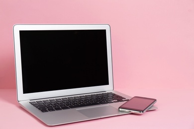 Photo of Modern laptop and mobile phone on color background