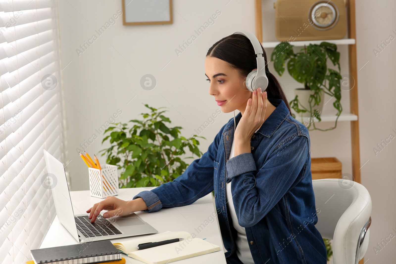 Photo of Woman in headphones studying on laptop at home. Online translation course