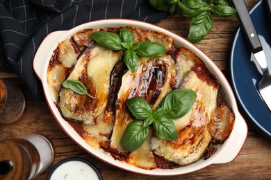 Photo of Delicious eggplant lasagna in baking dish on wooden table, flat lay