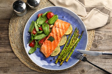 Photo of Tasty grilled salmon with tomatoes, asparagus, spinach and lemon served on table, flat lay