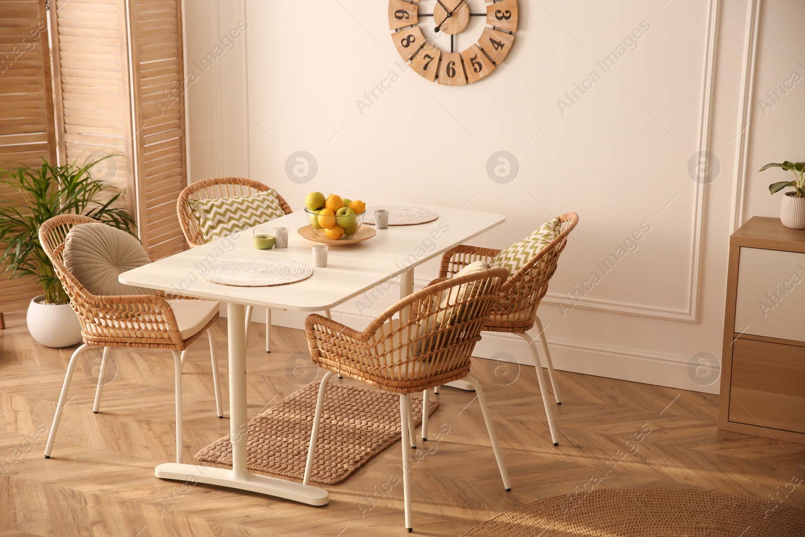 Photo of Stylish white dining table and wicker chairs in room. Interior design